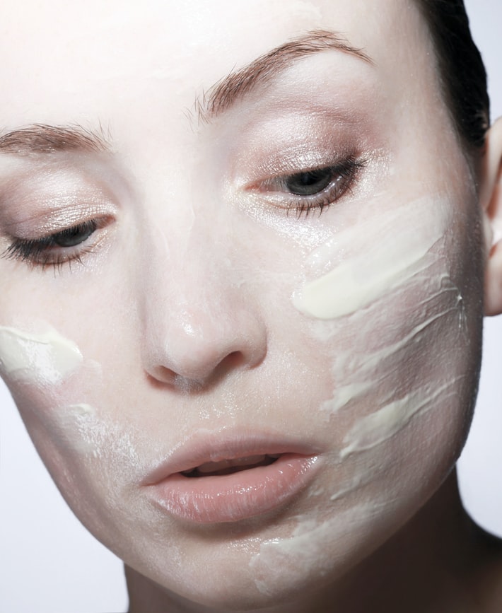 woman with white facial mask cream applied on her cheeks